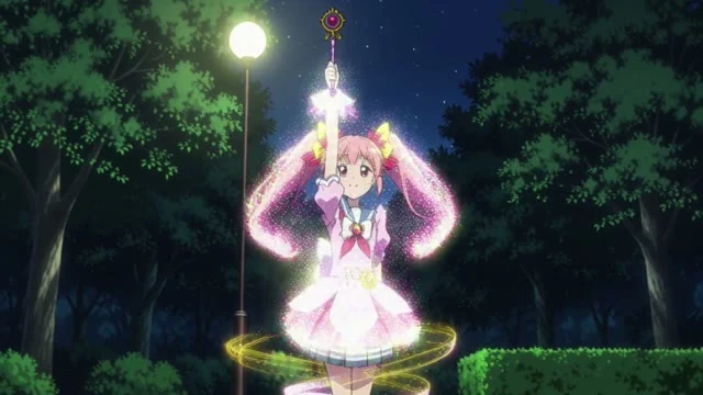 アニメのカット。魔法少女。夜の公園で、女子高生がステッキを掲げると光のリボンが体を包み、衣装が変わる。「いくよ」と言って笑う。